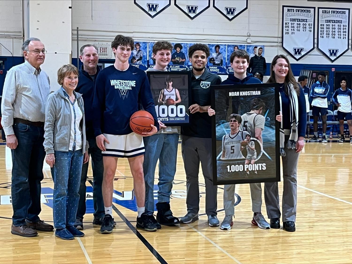 student posing in basketball uniform alongside members of family